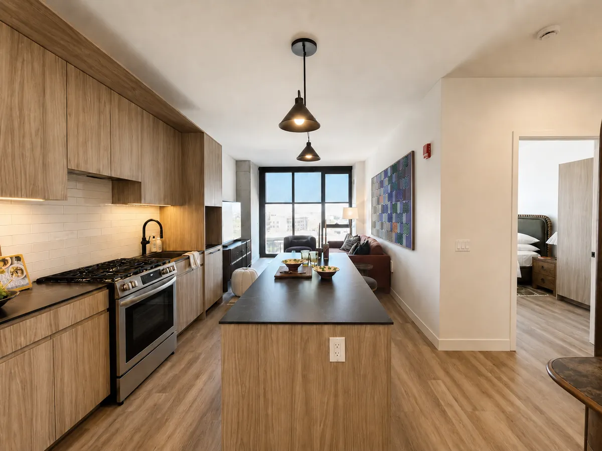 Kitchen in a Stead 220 apartment with wood cabinetry, stone countertop, and integrated appliances